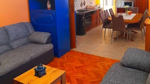 A compact living space with a sofa, a small wooden table, and a dining area with chairs and a table.