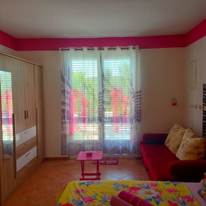 A room with a bed, a red sofa, a small table, and a wardrobe. - Pretty Apartment With Terrace on Island Rab (Rab)