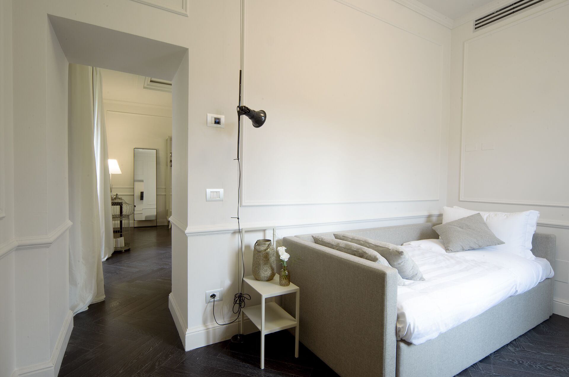 Un dormitorio moderno con cama, mesita de noche y espejo.