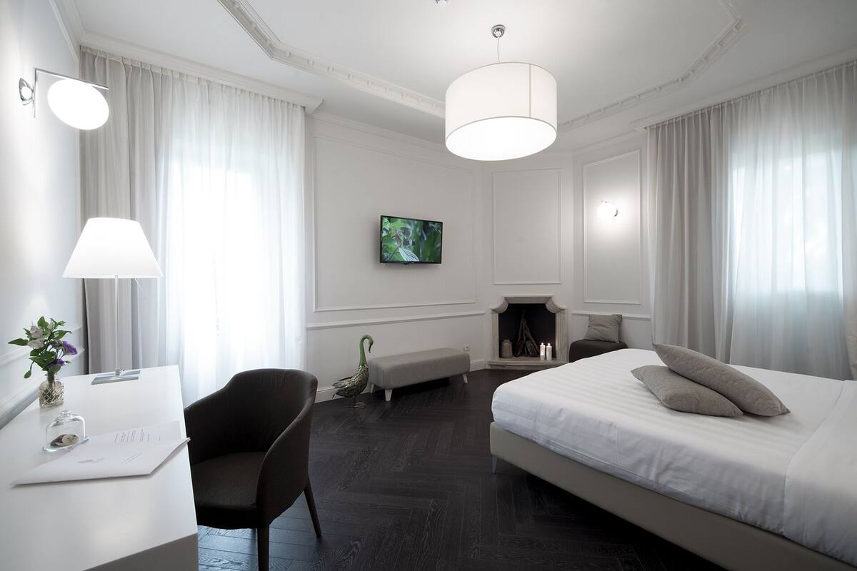 Una habitación de hotel moderna con una cama grande, un escritorio, una silla, un televisor y una chimenea.