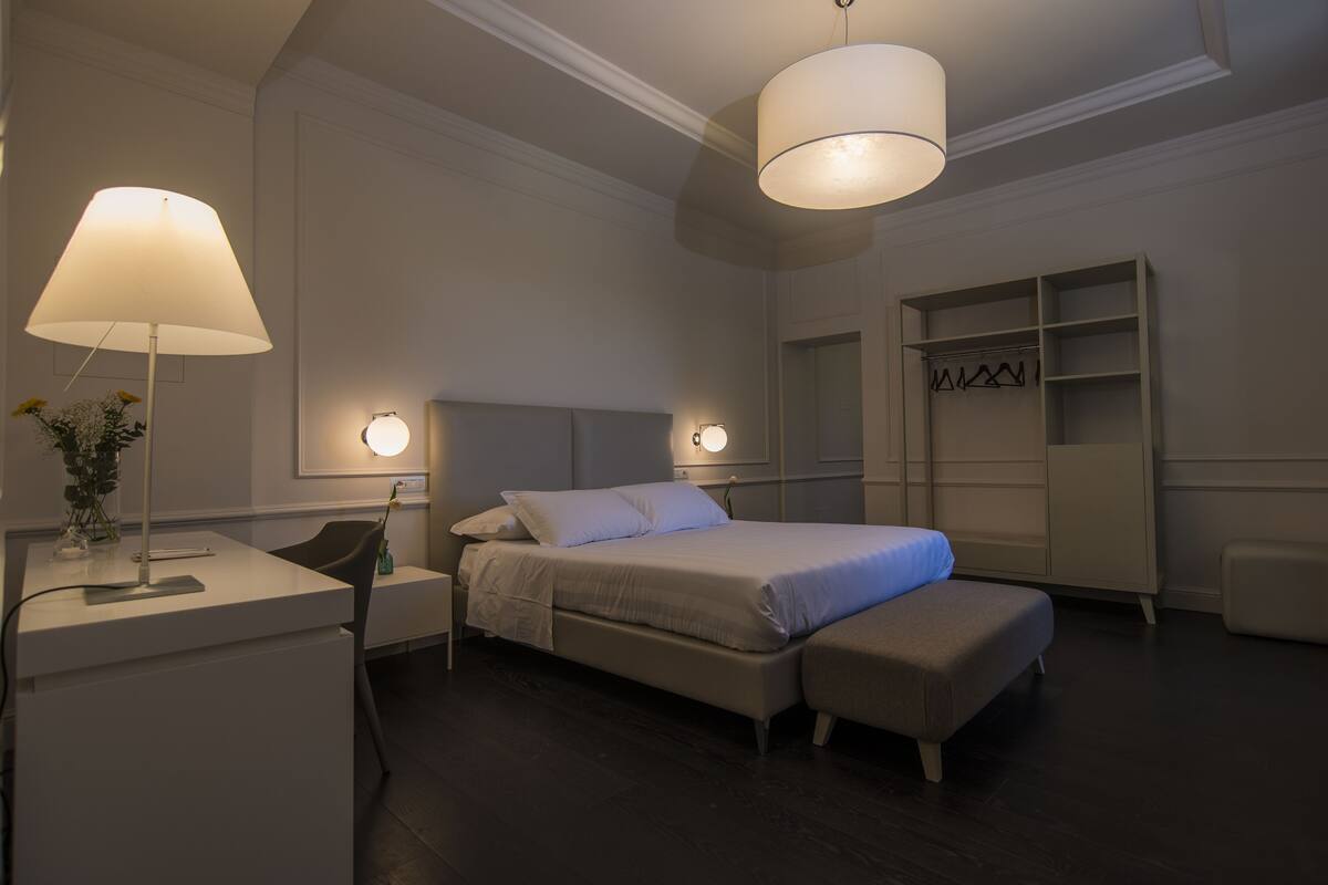 Un dormitorio moderno con cama, mesitas de noche, escritorio y armario.
