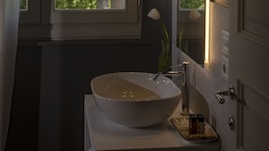Un bagno con una grande finestra, un lavandino bianco e uno specchio.