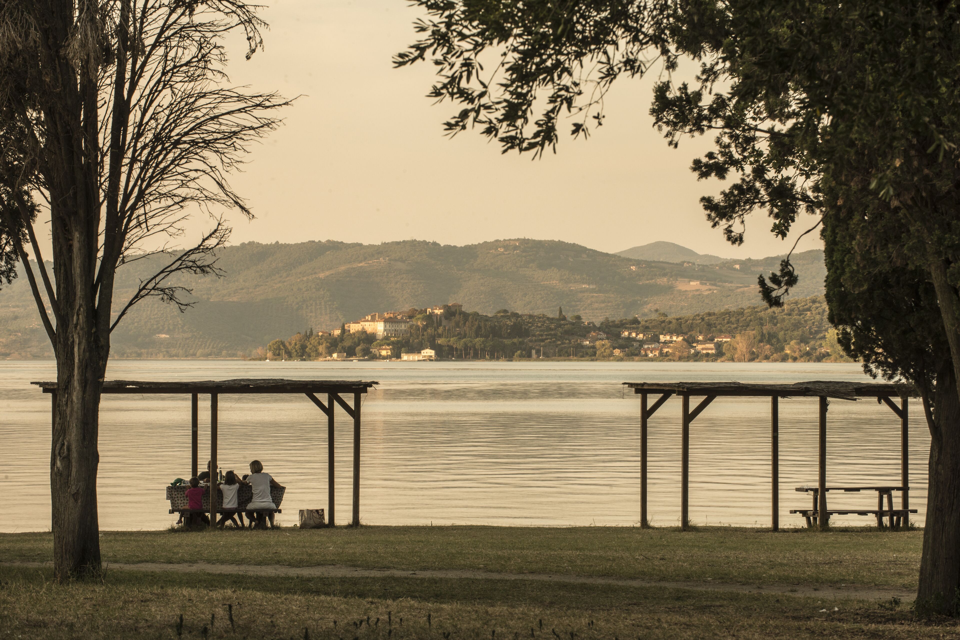 A lakeside park with picnic tables and a gazebo.