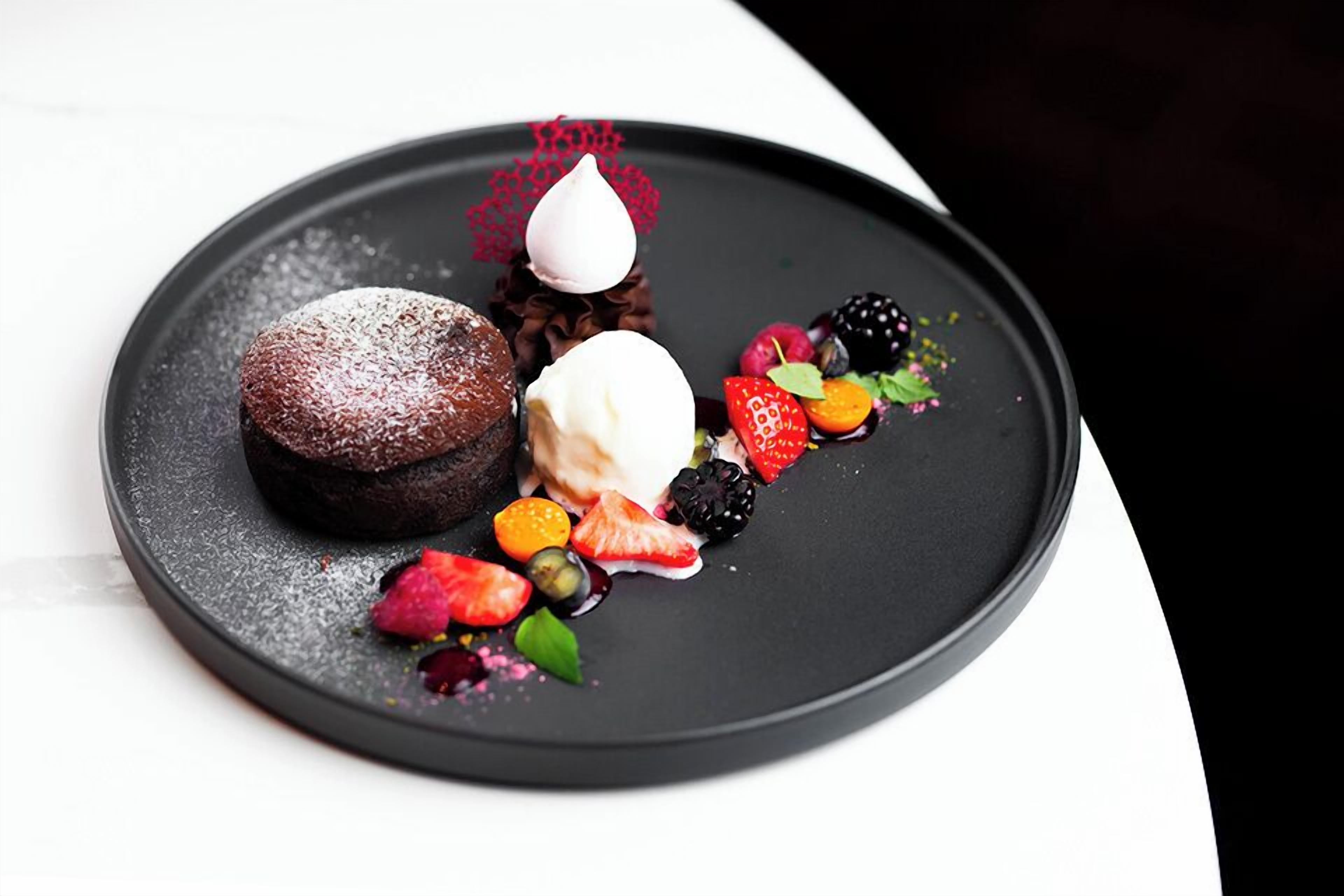 A dessert plate with a chocolate cake, ice cream, and assorted berries.