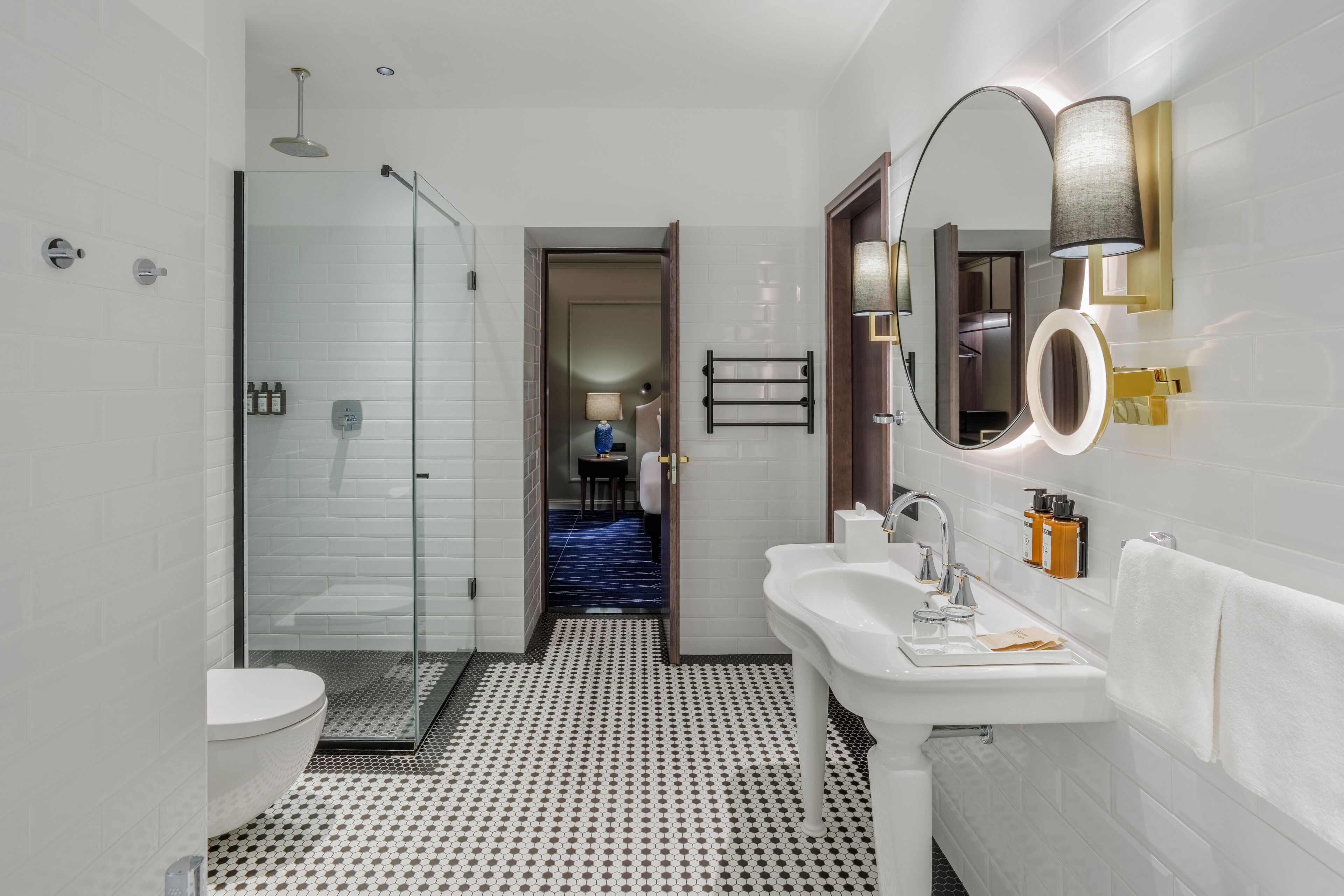 A modern bathroom with a glass shower enclosure, a white sink, and a mirror with a circular frame.