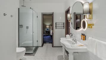 A modern bathroom with a glass shower enclosure, a white sink, and a mirror with a circular frame.