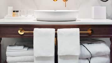A bathroom with a white sink, gold fixtures, and a mirror.