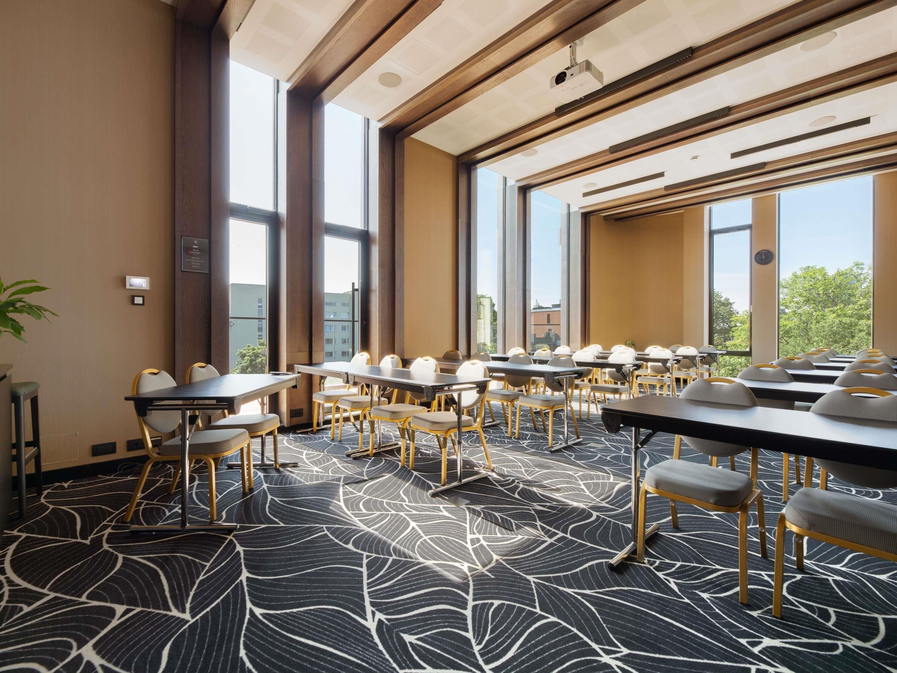 A conference room with large windows, a patterned carpet, and modern furniture.