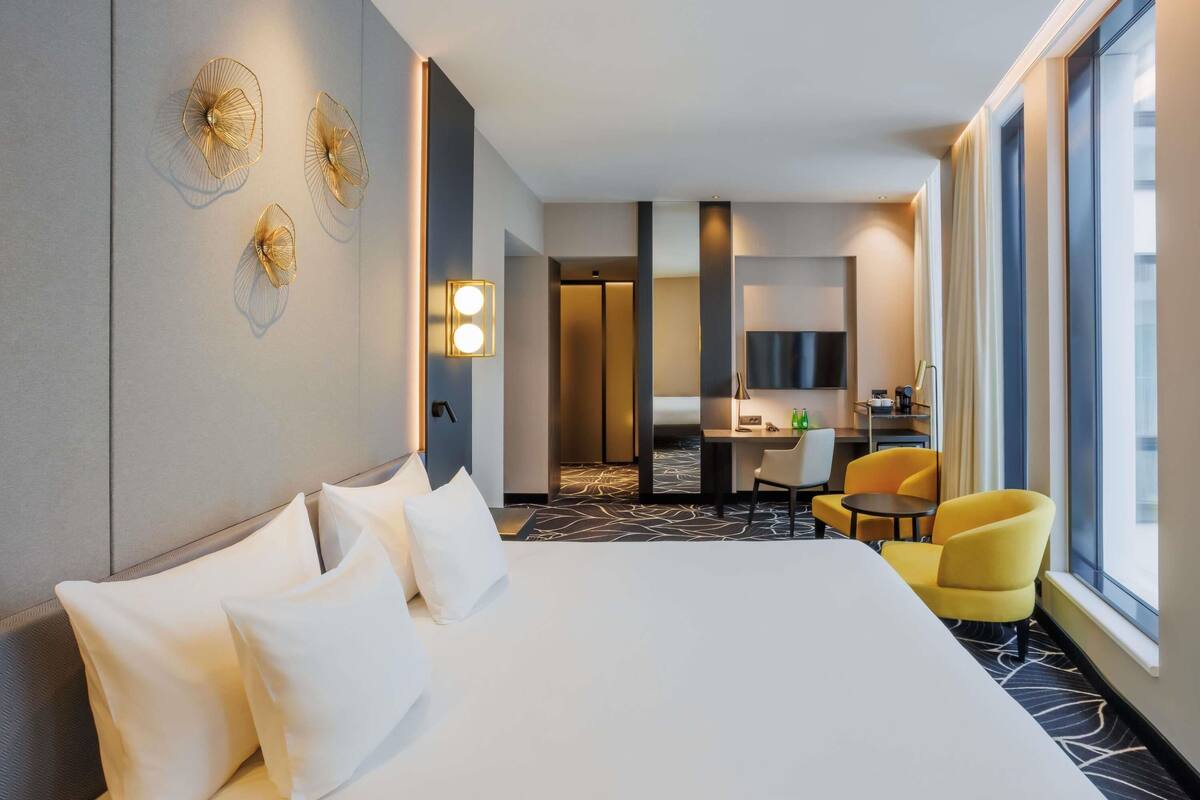 Ein Hotelzimmer mit einem großen Bett, einem Schreibtisch, einem Stuhl und einem Fernseher.