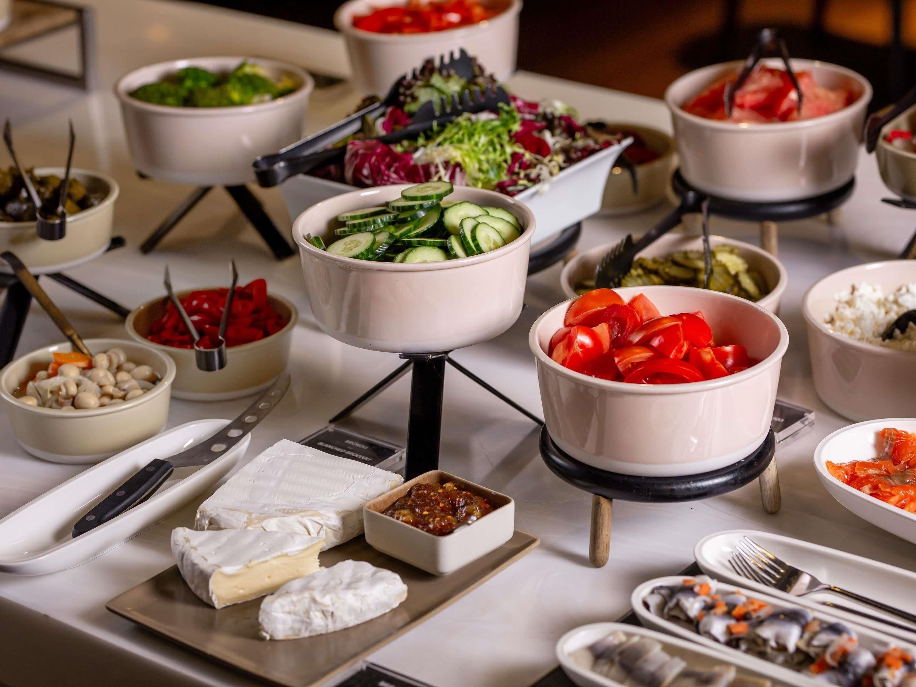 Un bufé con diversos alimentos, entre ellos verduras, queso y mariscos.