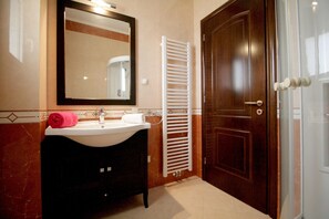 A bathroom with a sink, mirror, towel rack, and a door.
