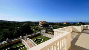 A balcony with a view of a coastal landscape, a stone bridge, and a pool. - Luxurious Villa Anthi (Chania)