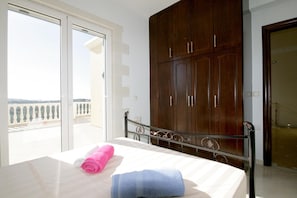 Ein Hotelzimmer mit Bett, großem Kleiderschrank und einem Balkon mit Blick.