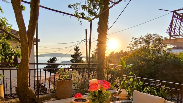 A balcony with a view of the sea, a potted plant, and a table with a cushion. - Apartment With Amazing sea View (Trogir)