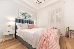Un dormitorio con cama, mesita de noche, lámpara y una obra de arte.