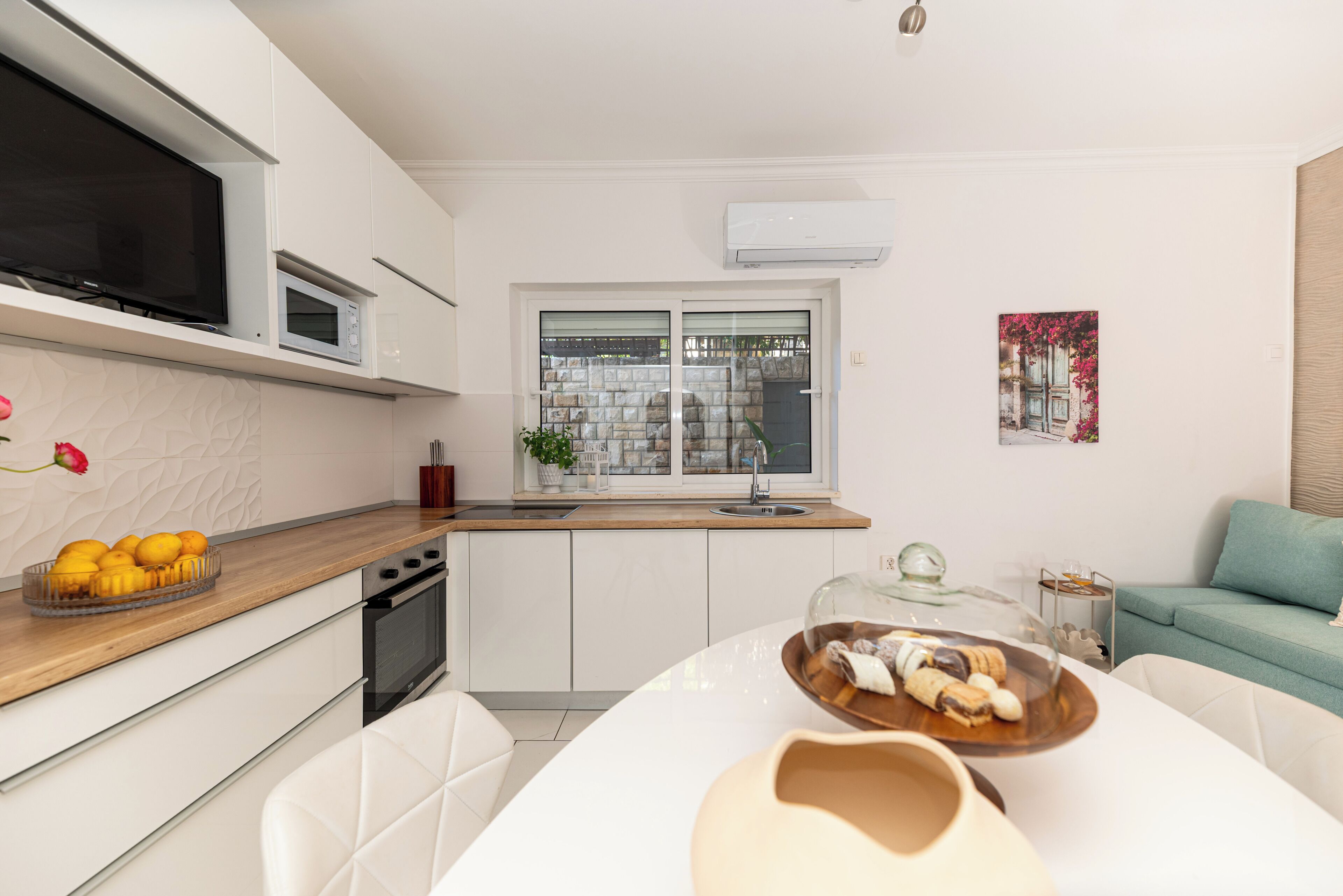 A modern kitchen with white cabinetry, a microwave, and a large window.