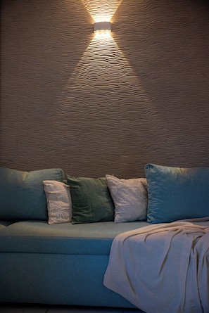 A room with a textured wall, a blue sofa with pillows, and a light fixture.