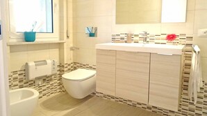 A bathroom with a toilet, bidet, and a sink with a mirror above it. - TWO-ROOM APARTMENT with balcony 50 meters from the SEA and 7 KM from SANREMO (Santo Stefano al mare)