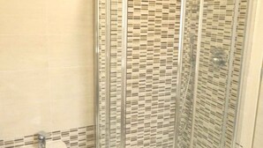 A bathroom with a glass-enclosed shower, a tiled wall, and a sink with a faucet. - STUDIO APARTMENT with balcony 50 meters from the SEA and 7 KM from SANREMO (Santo Stefano al Mare)