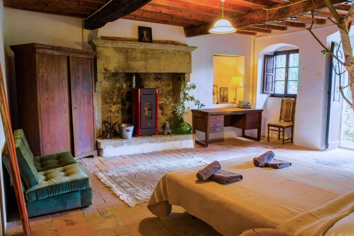 Un dormitorio rústico con chimenea de piedra, muebles de madera y vistas al exterior.