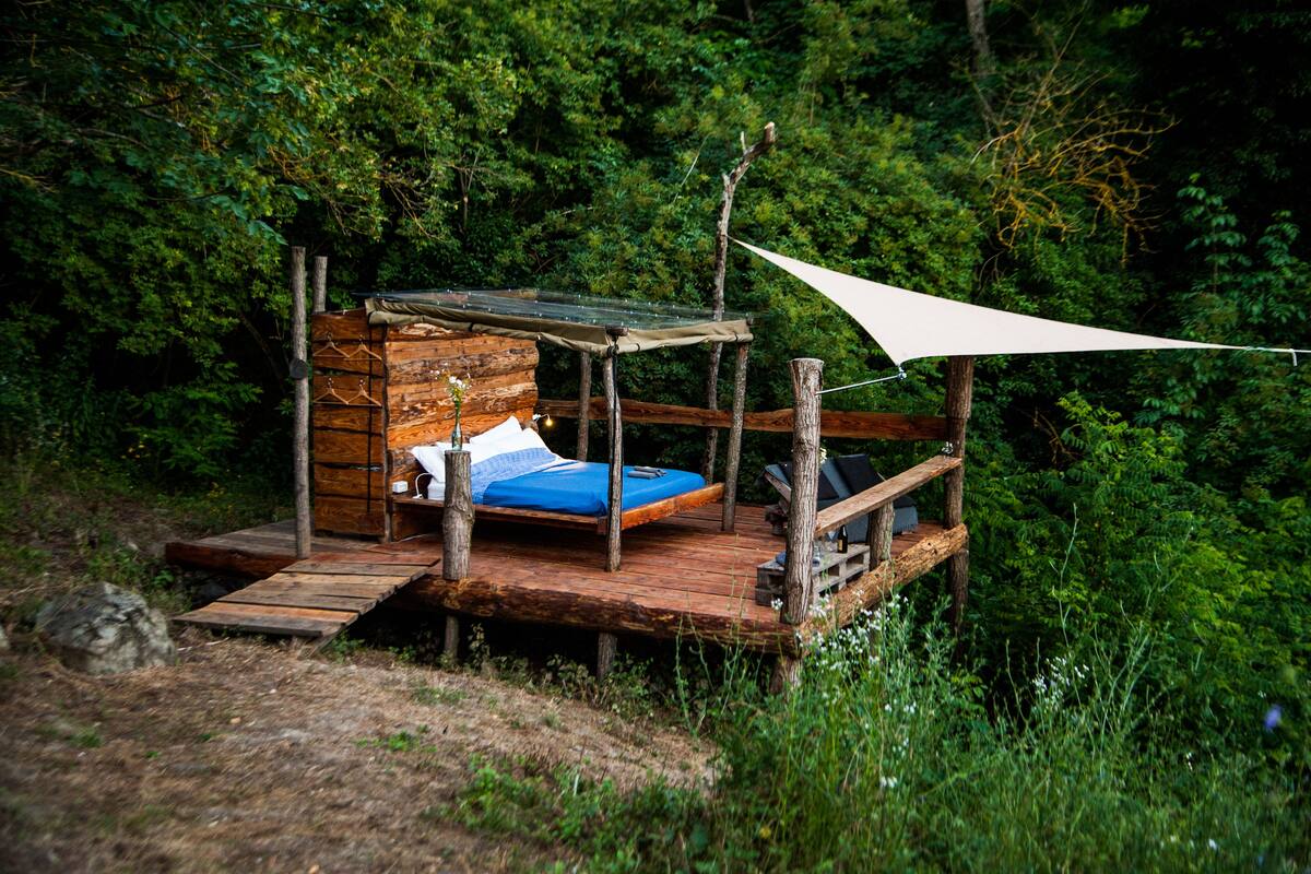 Una cabaña rústica de madera con una cama, una mesita y un banco.