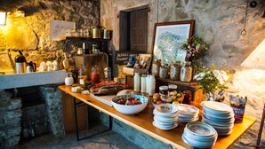 A rustic kitchen with stone walls, a wooden counter, and various food items and kitchenware. - Novanta (Bibbiena)