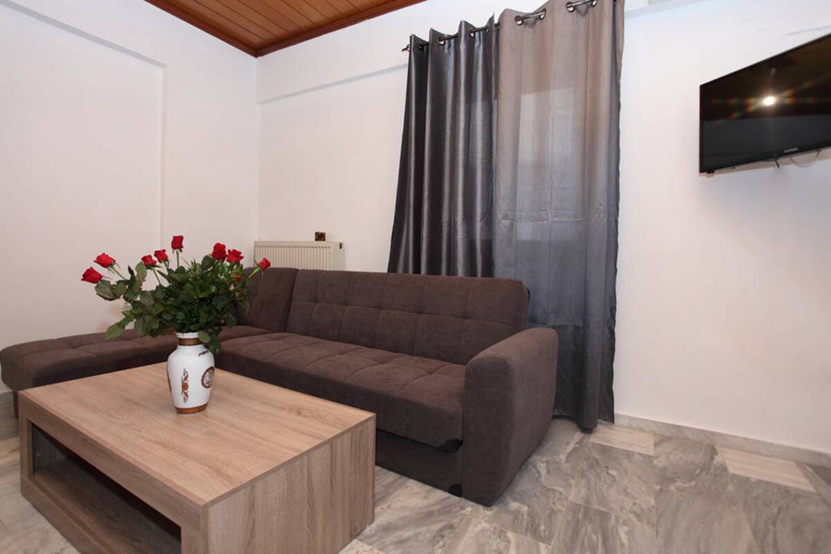 Ein Wohnzimmer mit einem braunen Sofa, einem Holztisch und einer Vase mit roten Blumen.