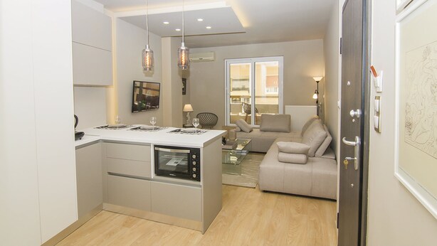 A modern kitchen with an island, a dining area with a glass table, and a living room with a sofa. - Contemporary Design In Central Athens (Athens)