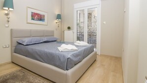 A bedroom with a bed, two wall-mounted lamps, a framed picture, a radiator, and a balcony door. - Contemporary Design In Central Athens (Athens)