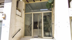 A building entrance with a glass door, a metal handrail, and a potted plant. - Contemporary Design In Central Athens (Athens)