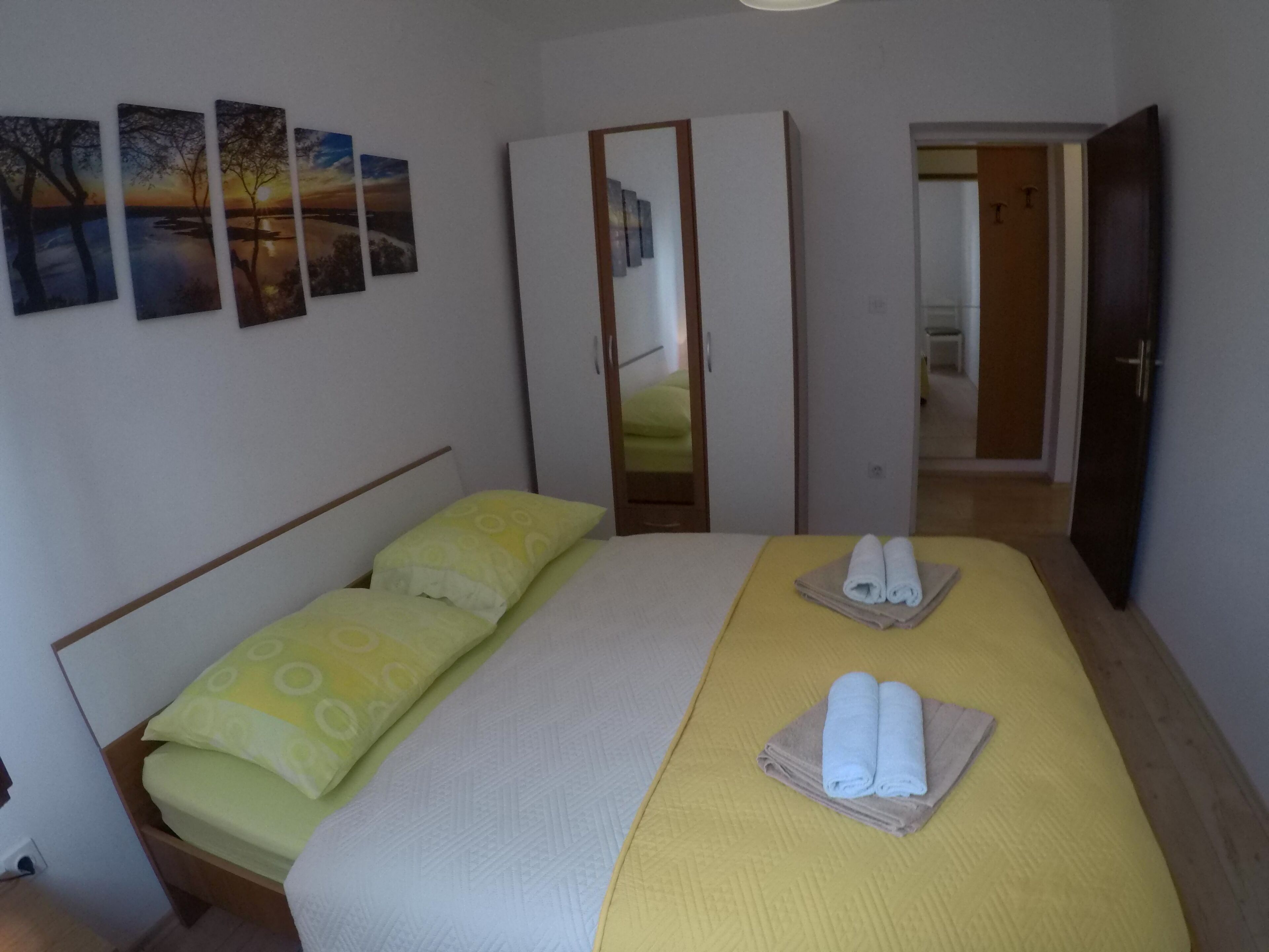A bedroom with a bed, pillows, a mirror, and a wardrobe.