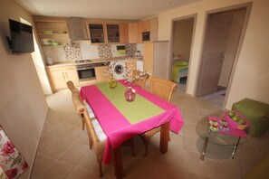 Cozy living space with a dining area and kitchenette, featuring a table, chairs, and a TV.