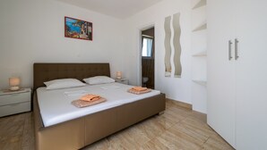 Une chambre moderne avec un grand lit, une table de chevet avec une lampe, un tableau au mur et une armoire.
