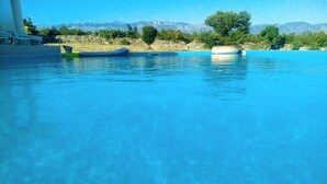 Une piscine d’eau bleue et limpide, avec une vue sur les montagnes en arrière-plan.