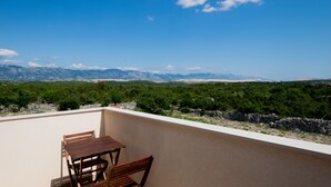 Un balcon avec une table et des chaises, donnant sur un paysage montagneux.
