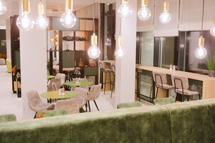 Un interior moderno con mesas redondas, sillas acolchadas y lámparas colgantes.