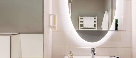 A bathroom with a white sink, a mirror, and a towel rack.