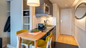 A compact kitchen with a dining table, chairs, and a microwave. - Aparthotel Adagio Access Freiburg (Freiburg im Breisgau)