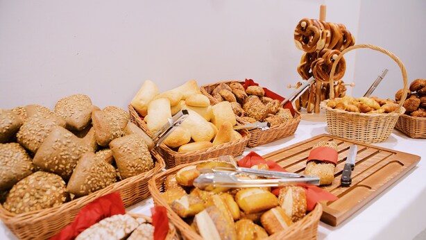 A variety of breads and pastries displayed in wicker baskets on a table.