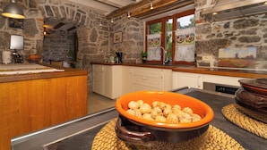 A rustic kitchen with stone walls, wooden beams, and a large orange bowl of walnuts on the counter. - Luxurious Villa in Ružići Croatia With Private Pool and Garden (Matulji)