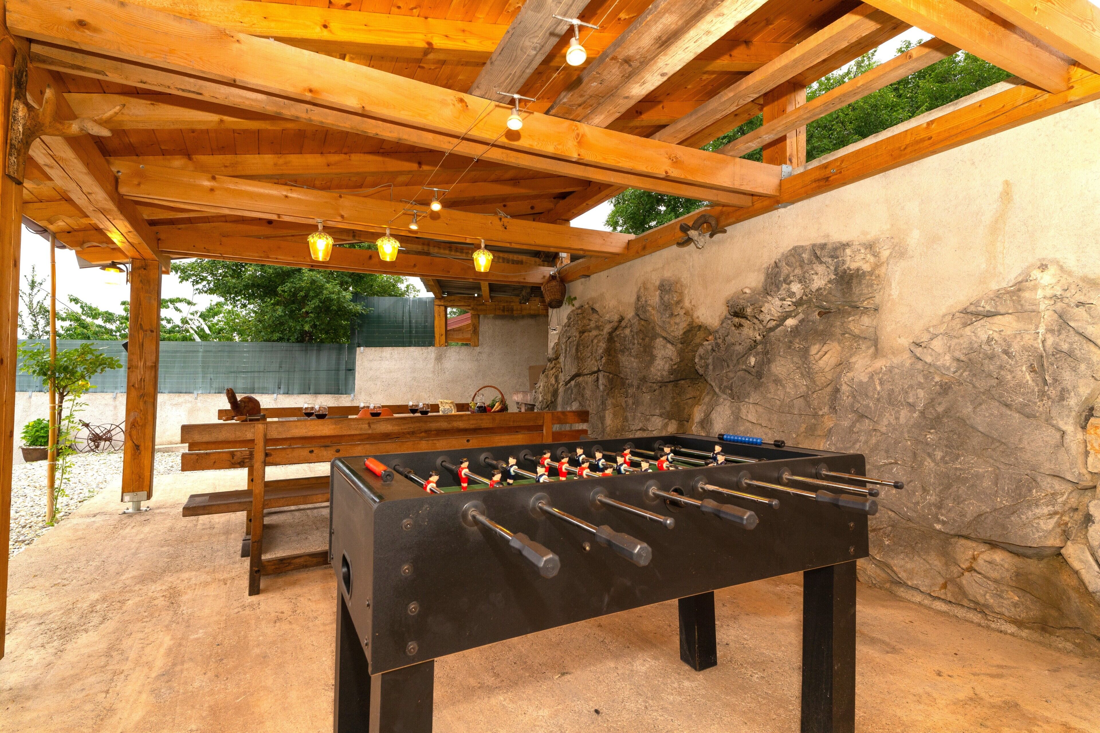 A wooden-floored indoor area with a foosball table, benches, and hanging lights.