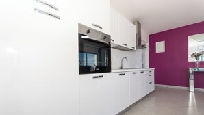 A modern kitchen with white cabinets, a black oven, and a purple accent wall. - In Center Near the Marina and Beach With Amazing View (Tribunj)