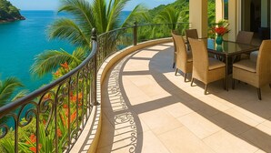 A balcony with a curved railing, a dining table with chairs, and a view of the ocean and greenery. - Truly one of the Finest Villa for Rent in Puerto Vallarta (Puerto Vallarta)