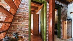 Une pièce aux murs en briques apparentes, avec des poutres en bois et un cadre de porte vert.