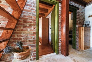 Une pièce aux murs en briques apparentes, avec des poutres en bois et un cadre de porte vert.
