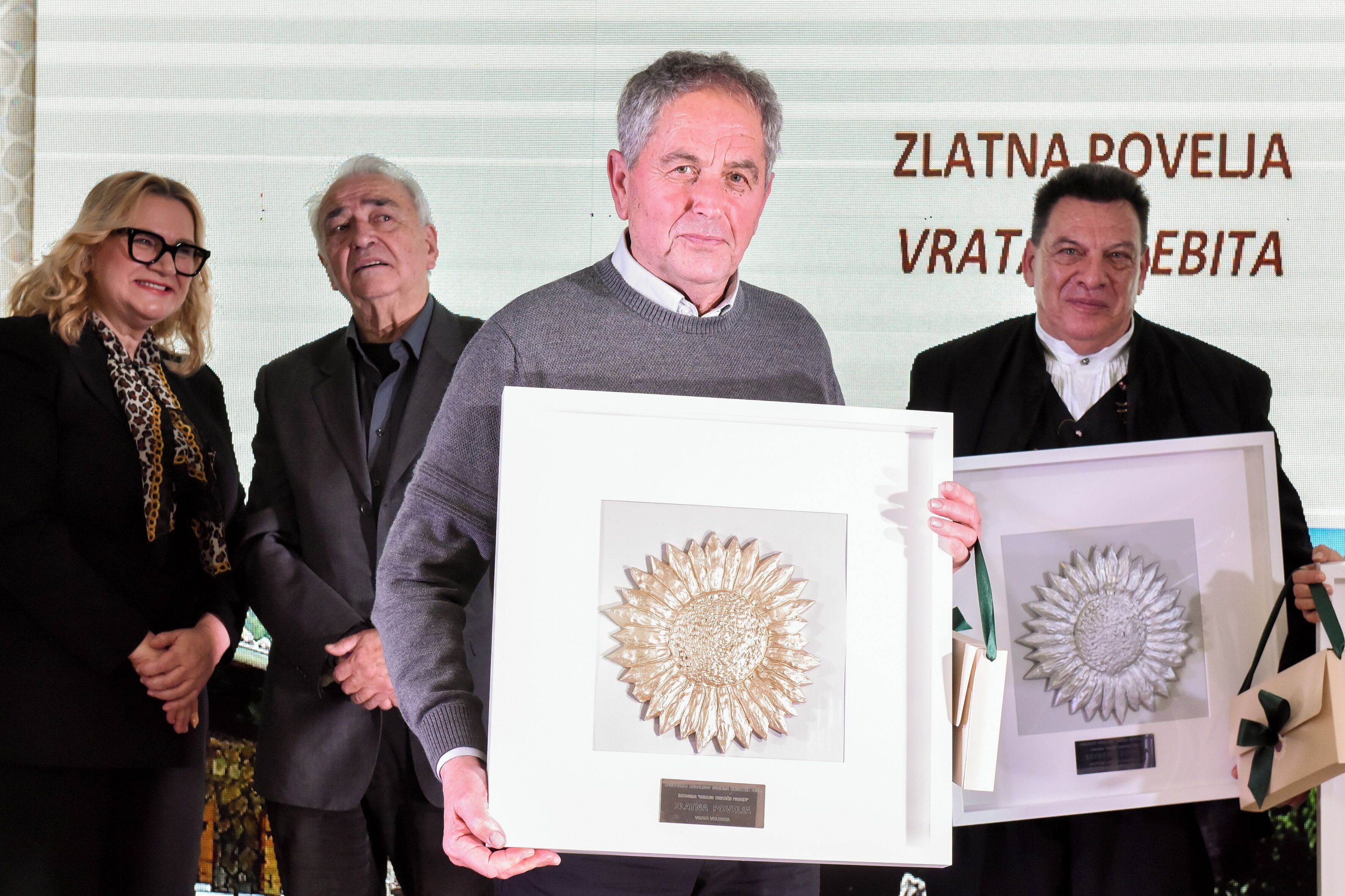 A group of people holding framed artworks at an event.
