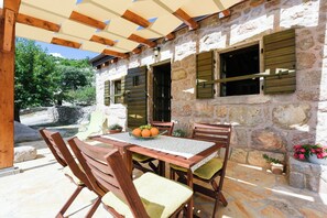 Une terrasse extérieure avec un mur en pierre, une table en bois et des chaises.