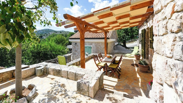 Une terrasse extérieure avec un sol en pierre, des meubles en bois et une pergola.