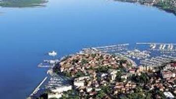 An aerial view of a coastal town with a marina, dense greenery, and a clear blue sea.