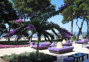 An outdoor seating area with purple and yellow cushions, surrounded by trees and a clear sky. - Room in Apartment - Great Location Just a Short Walk From the Beach and Downtown Biograd - 4 Guests! (Biograd na Moru)